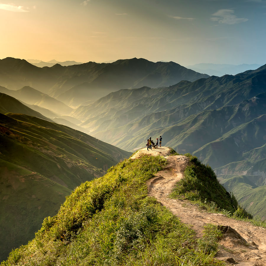 Group of hikers preparing meal on camping stove at high altitude mountain campsite