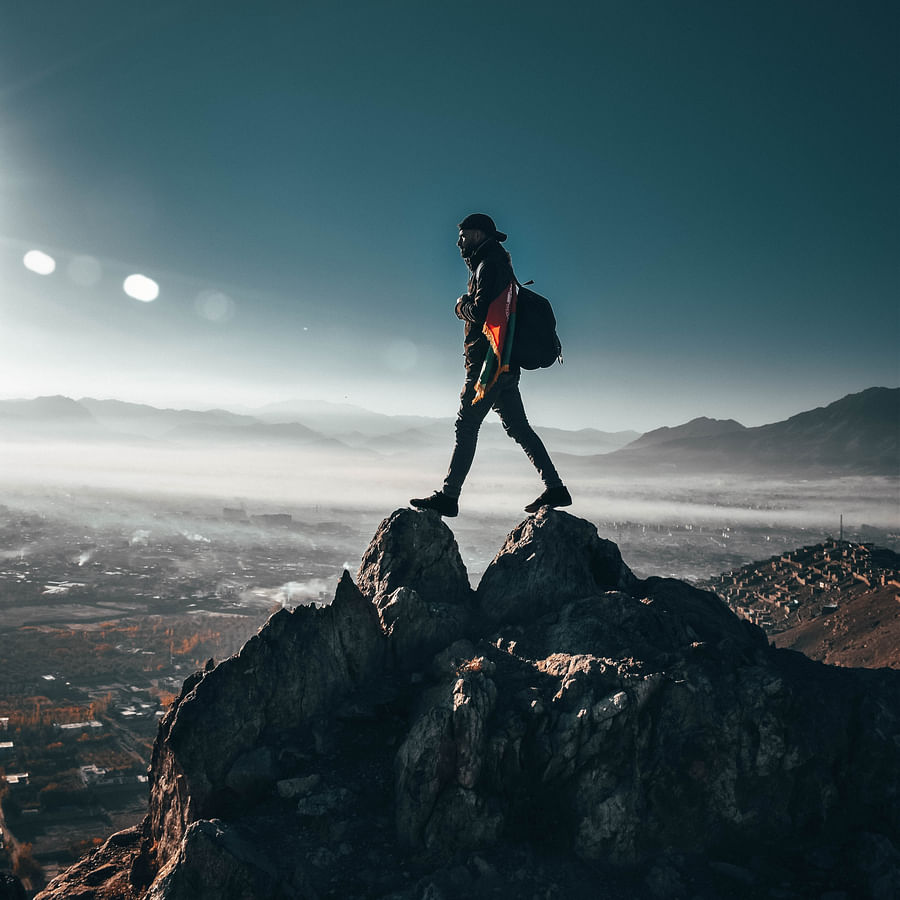 Mountain climber cooking on a portable stove with breathtaking mountain landscape in the background